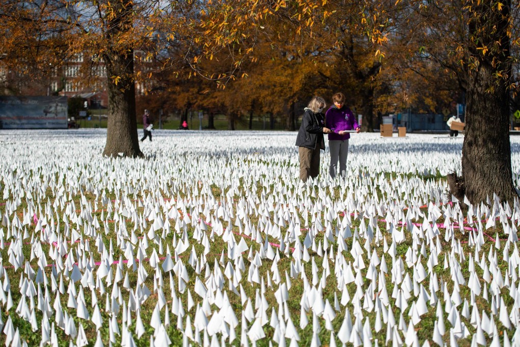 People are surrounded by a sea of white flags planted in memory of coronavirus victims in an art installation titled “In America how could this happen...” in Washington on December 1. Photo: AFP