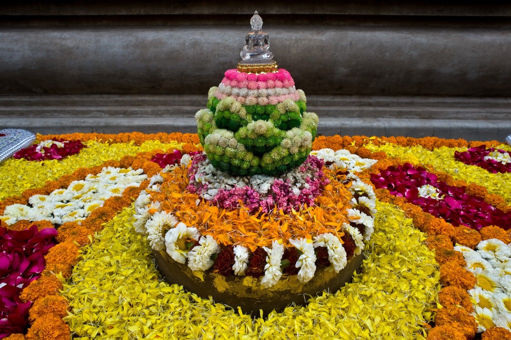 Flowers sit on and around a Buddhist statue at the Mahabodhi temple in Bodh Gaya, Bihar, India. Small companies are recycling some of the flowers left at India’s temples once they die. Photo: Getty Images