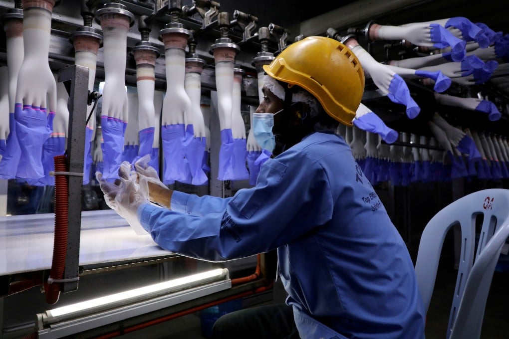 A Top Glove employee inspects newly-made gloves at one of the company’s factories in Shah Alam, Malaysia, before a coronavirus outbreak interrupted production. Photo: Reuters