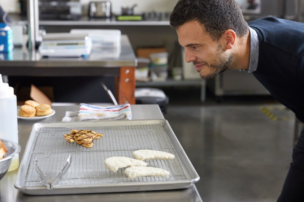 An employee of Eat Just inspects grilled fillet made from lab-grown cultured chicken. Photo: via Reuters