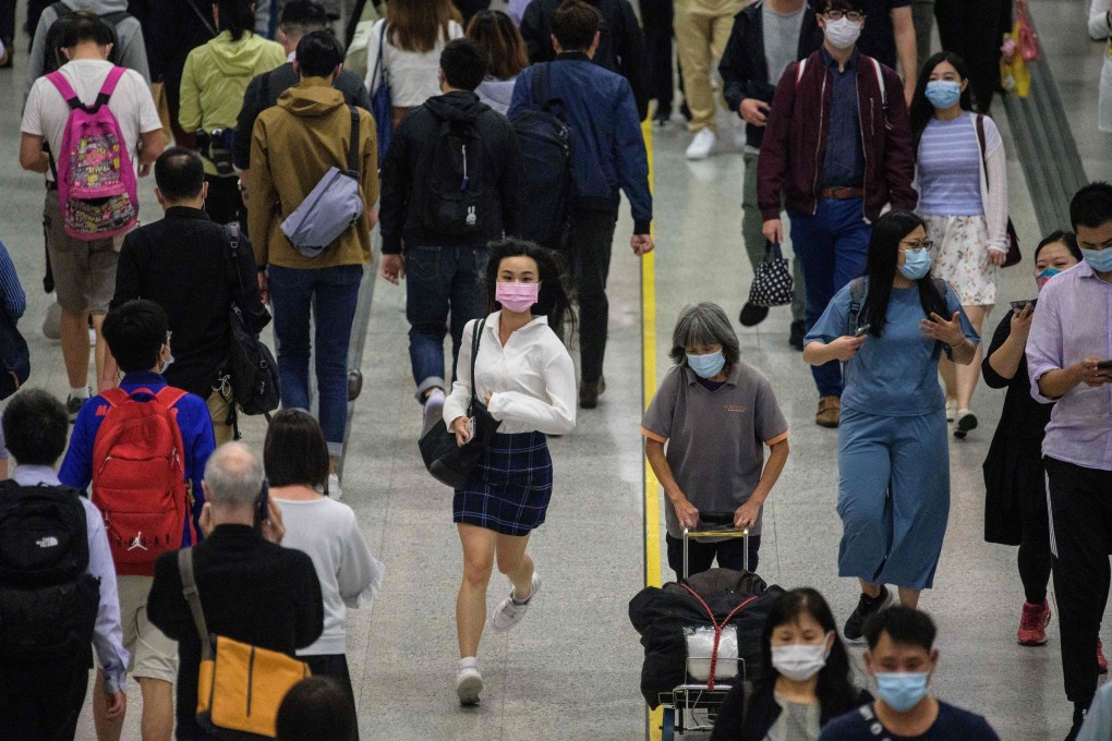 A woman wearing a facemask runs past other commuters walking in an MTR underground metro station. Photo: AFP