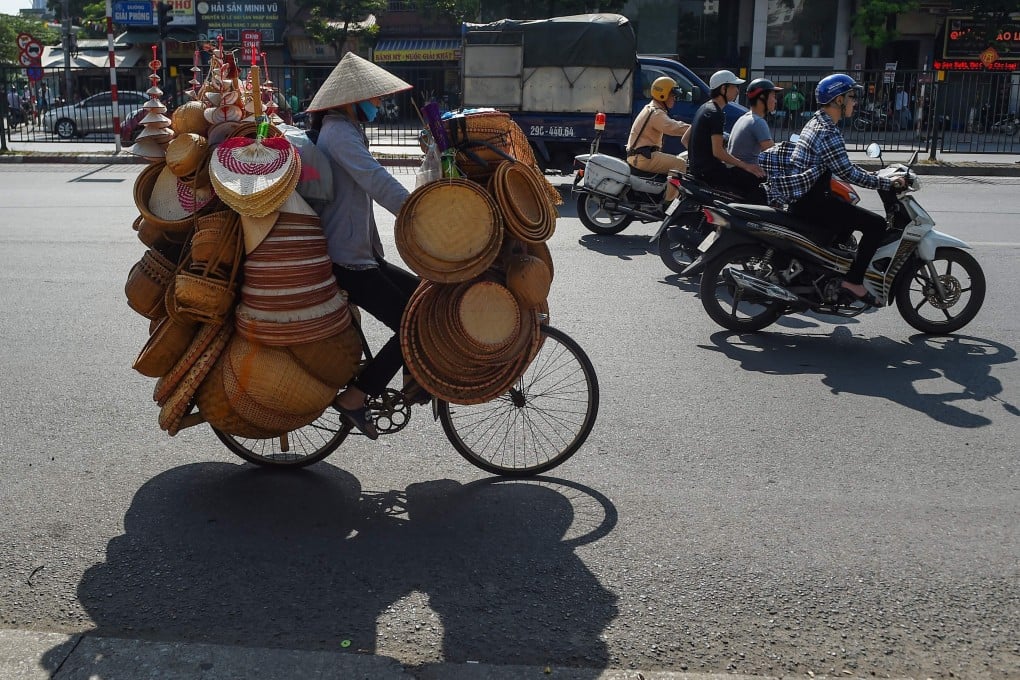 Motorists and a street vendor ride down a street in Hanoi. Photo: AFP