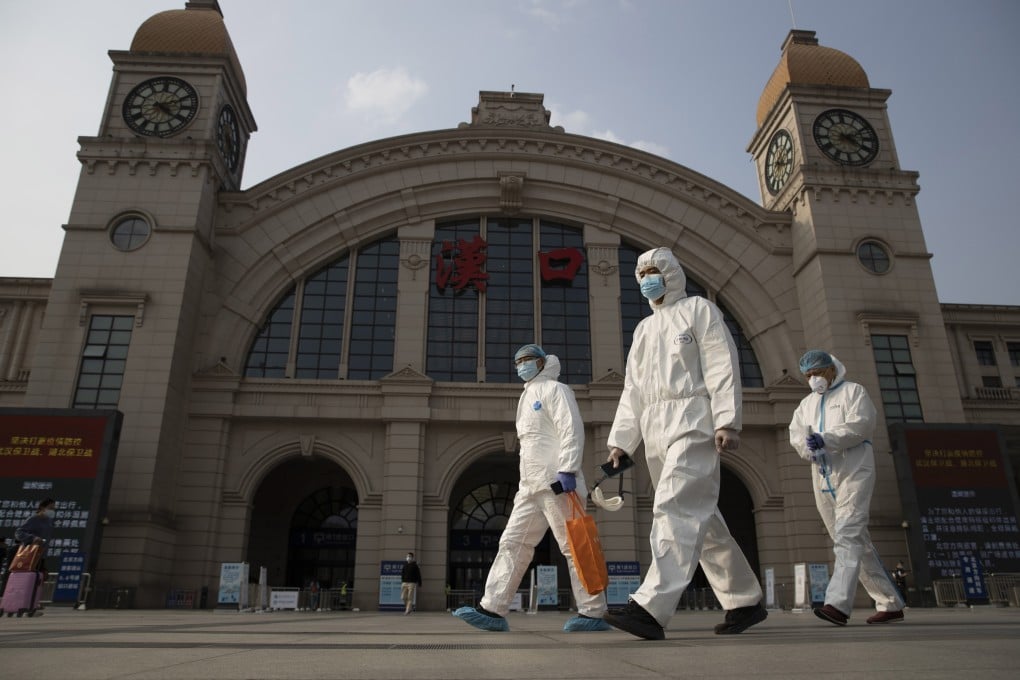 Workers in protective suits walk past the Hankou railway station in Wuhan in April. Photo: AP