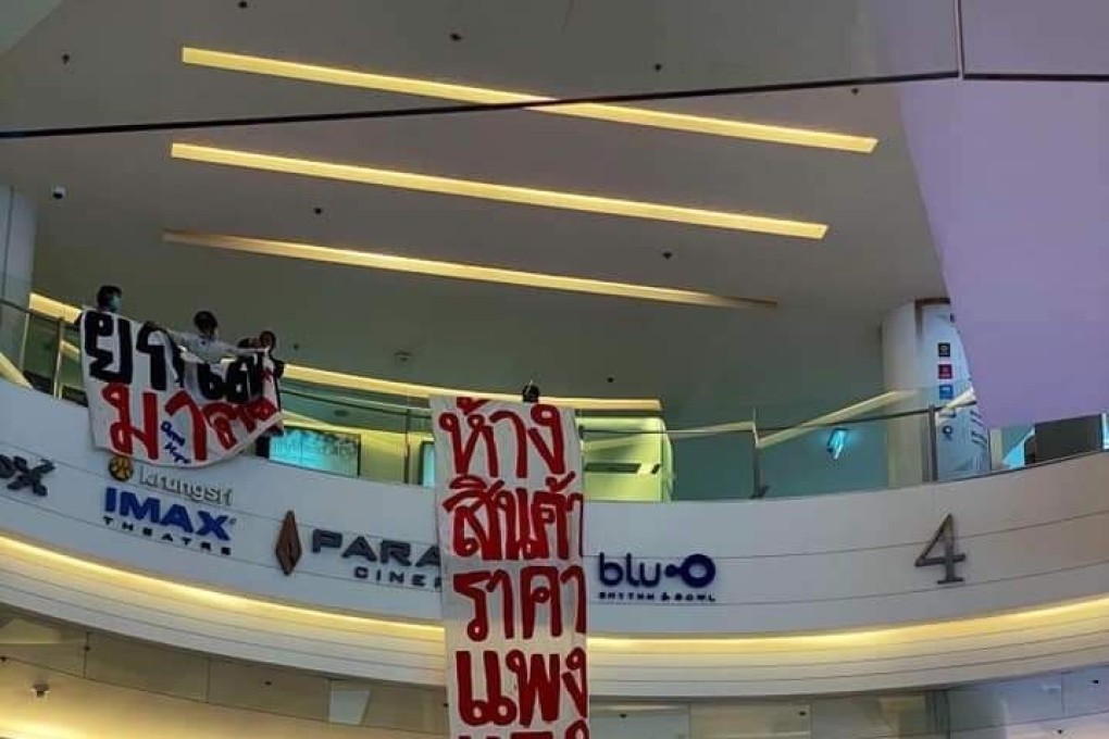 Protesters at Siam Paragon mall unfurling banners. The one on the left proclaims “Abolish Section 112", and the long one next to it reads “Expensive goods from cheap labour”.