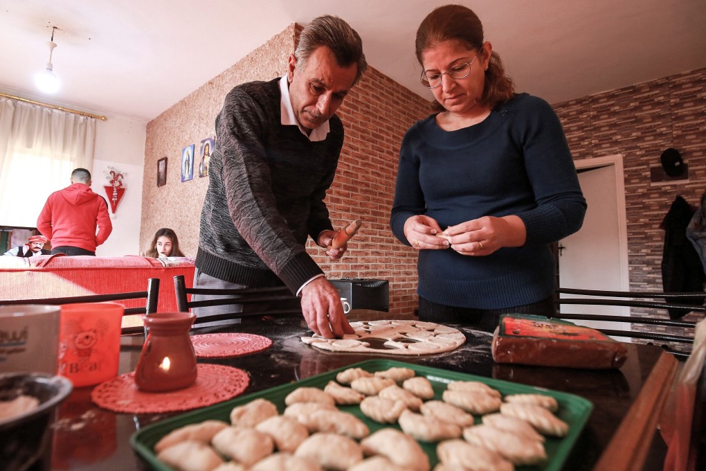 Saad Polus Qiryaqoz, left, prepares Christmas treats with his wife at their new home in Jordan's capital, Amman. Photo: AFP