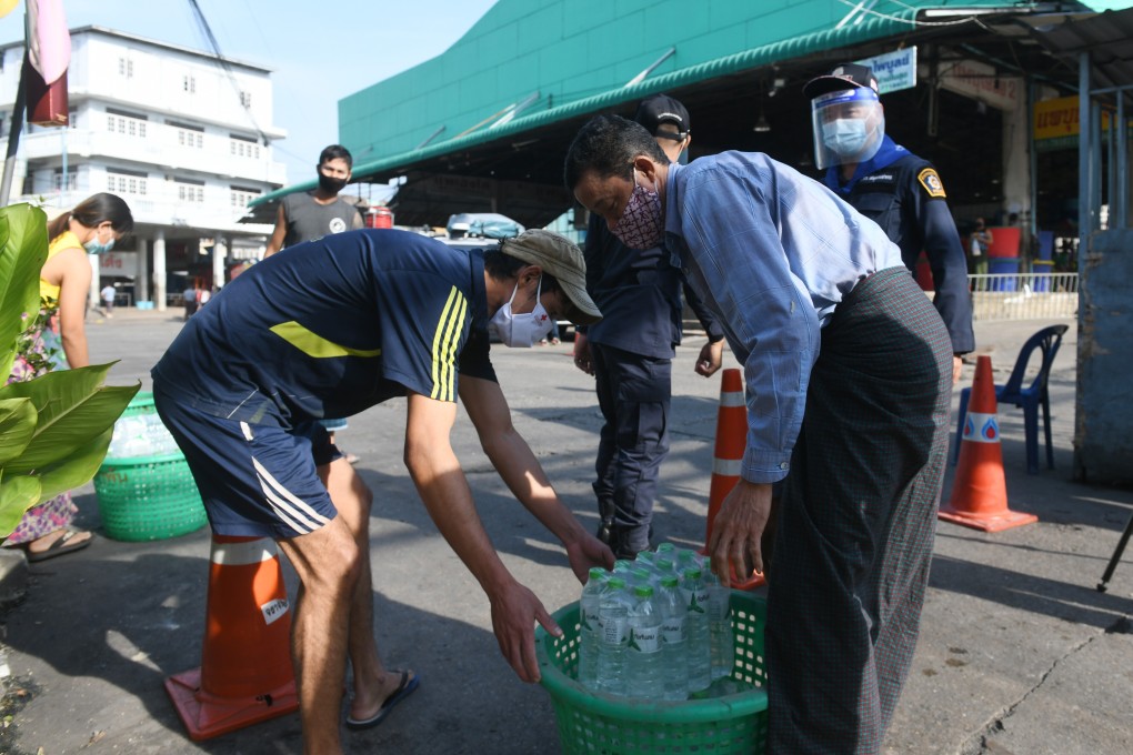 Staff members deliver drinking water to people living in the lockdown area near a seafood market in Samut Sakhon, Thailand on Saturday. Photo: Xinhua