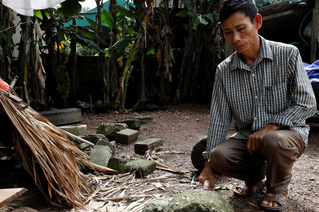 Nguyen Dinh Gia, the father of victim Nguyen Dinh Luong, kneels in his yard in Ha Tinh province, Vietnam. He said he feels sorry for the two men convicted of manslaughter as they were only trying to make a living. Photo: Reuters