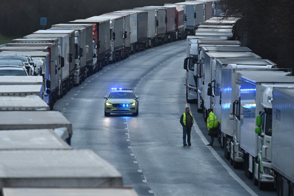 A police car passes long lines of freight lorries and goods vehicles on a closed section of the motorway leading to the Port of Dover in England on Tuesday. Photo: AFP