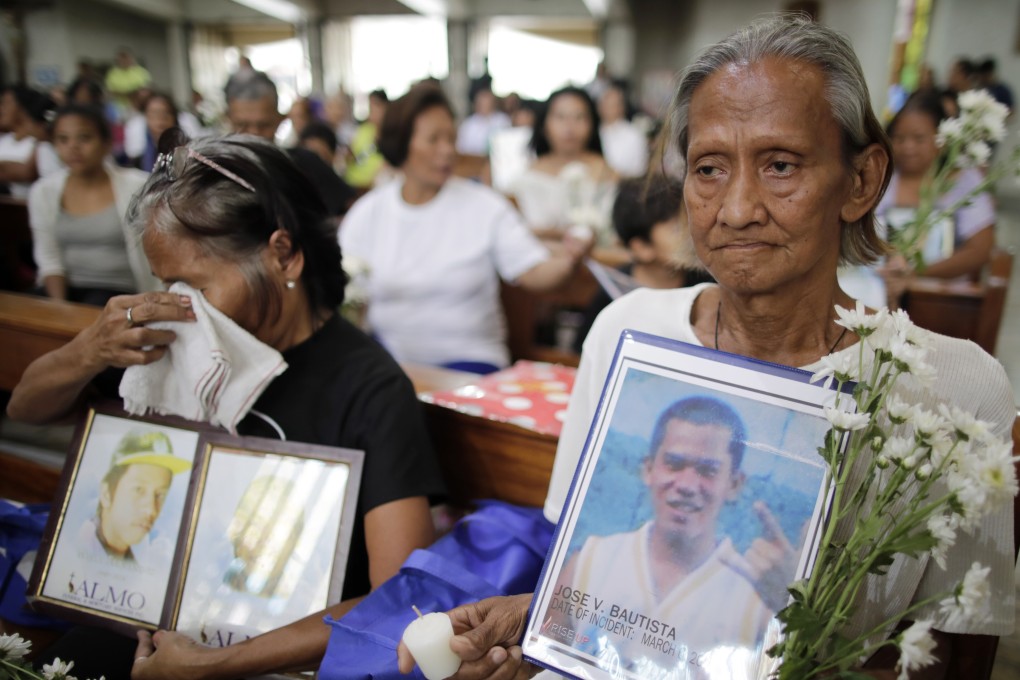 Filipino relatives of victims of drug-related killings hold pictures as they attend a Manila church mass in March 2019 in support of a complaint against President Rodrigo Duterte filed at the International Criminal Court. Photo: EPA-EFE