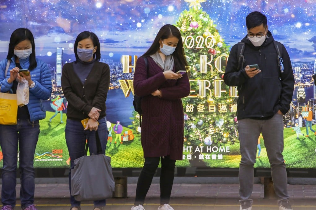 People wait for a bus in front of an Christmas advertisement in Central. Photo: Martin Chan