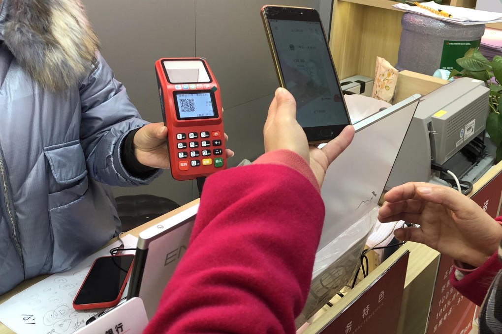 Li Lan, who won a 200-yuan red packet in Suzhou’s e-yuan test, scans a QR code with her smartphone to make a payment at an electronics shop. Photo: Orange Wang