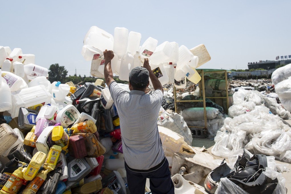 A man adds plastic containers to a heap of discarded plastic in Shanghai. China generates more than 80 million tonnes of plastic waste a year, and has vowed to reduce the total next year. Cities have begun implementing curbs on plastic usage, such as a ban on plastic straws in Chengdu. Photo: AFP