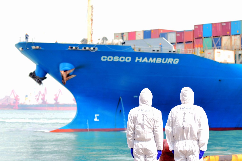 Port employees in protective suits watch a loaded container ship at Qingdao port in Shandong. China is the largest supply country for seafarers, so the vaccination of the Chinese maritime workforce will become an acute public health issue. Photo: DPA
