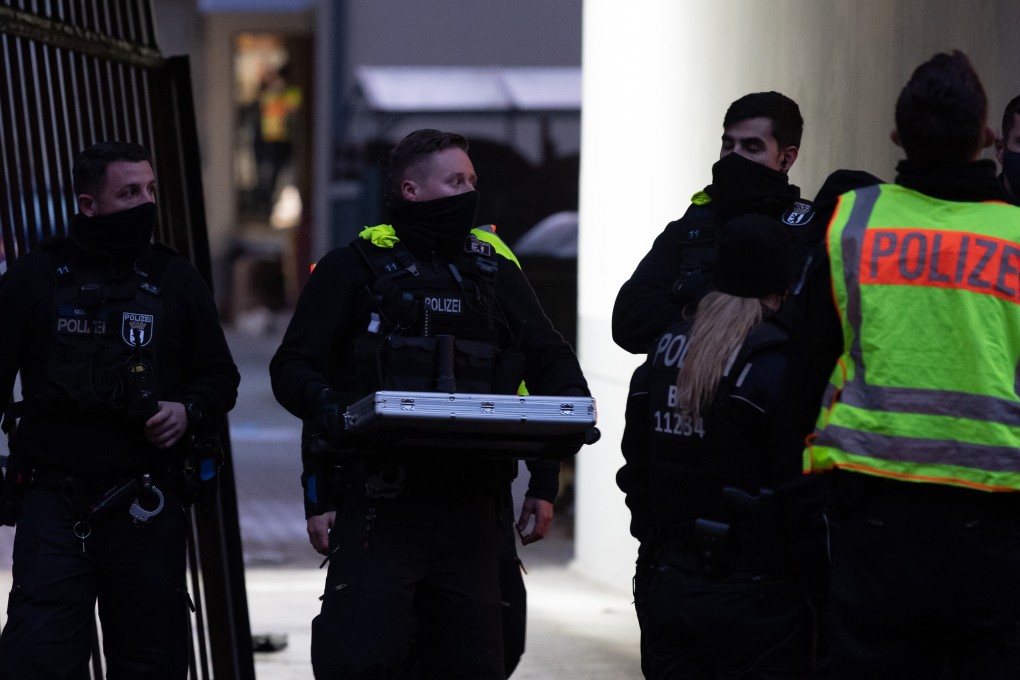 Police officers carry a suitcase out of a house on Stresemannstrasse in Kreuzberg, Berlin, where shots were fired and four men seriously injured. Photo: DPA