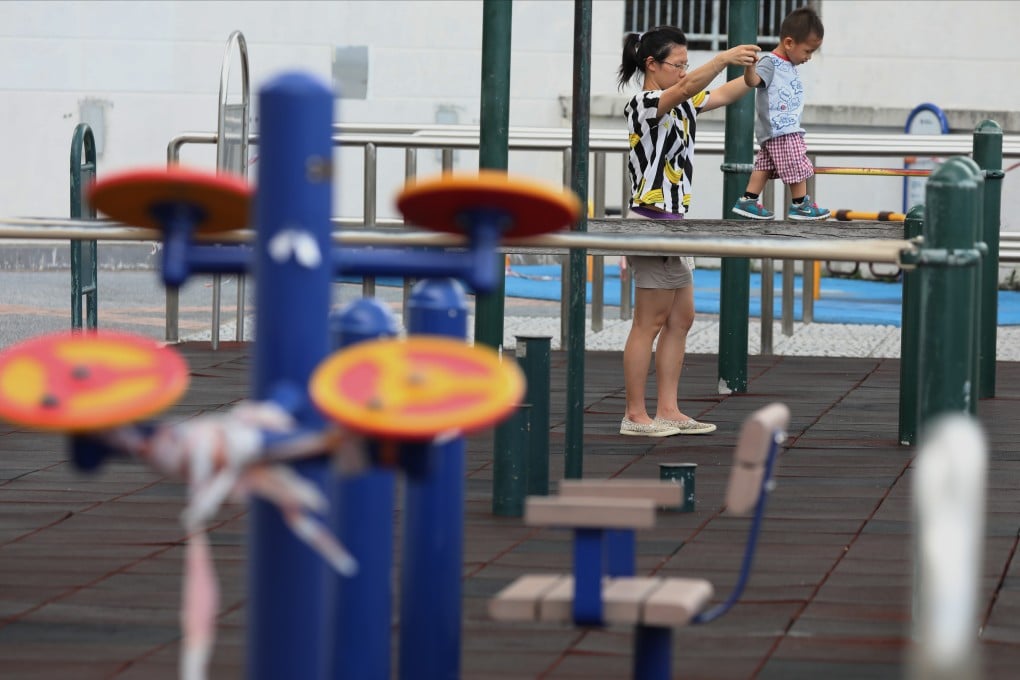 A mother holds her child’s hands as he walks across a beam at a playground in Aberdeen on June 22. Photo: Nora Tam