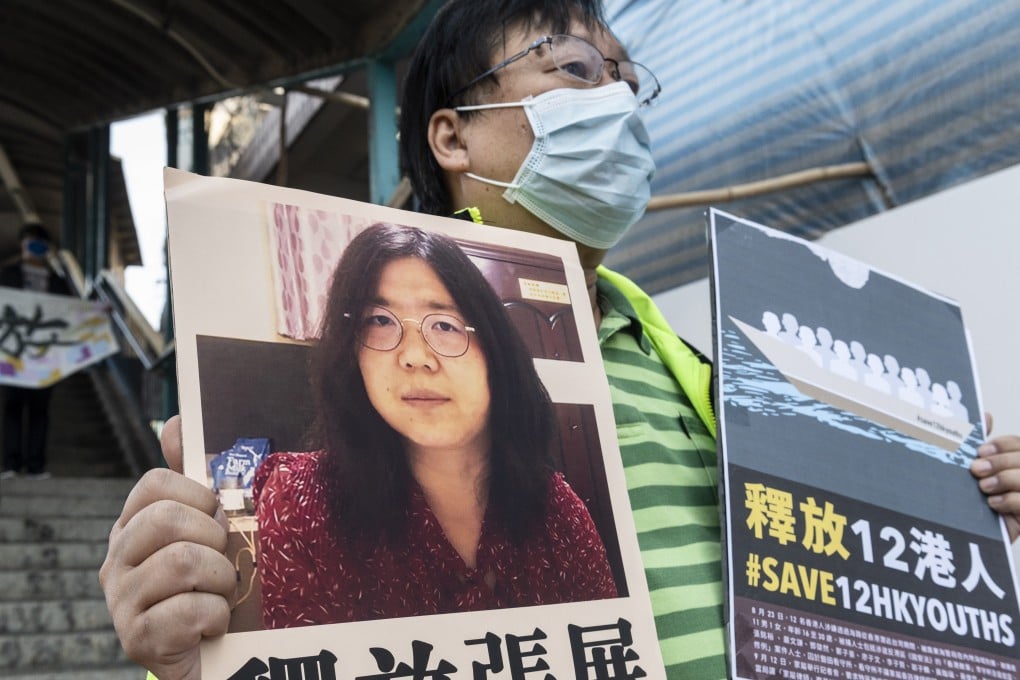 A pro-democracy activist holds up signs in support of Zhang Zhan and the 12 detainees arrested at sea outside Beijing’s liaison office in Hong Kong on Monday. Photo: EPA-EFE