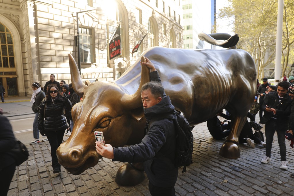 A Chinese tourist taking photos in front of the "Charging Bull" sculpture in lower Manhattan in New York City. Global stocks rallied from New York to Seoul and Shanghai in 2020 as investors turned a crisis year into outsized gains. Photo: AFP