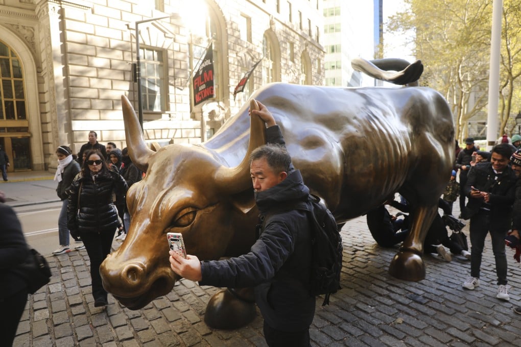 A Chinese tourist taking photos in front of the "Charging Bull" sculpture in lower Manhattan in New York City. Global stocks rallied from New York to Seoul and Shanghai in 2020 as investors turned a crisis year into outsized gains. Photo: AFP