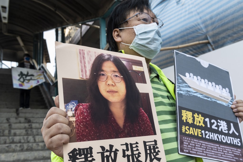 An activist near Beijing’s liaison office in Hong Kong holds up signs to support Zhang Zhan and a group of 12 Hongkongers detained on the mainland for over 130 days, on December 28. Photo: EPA-EFE