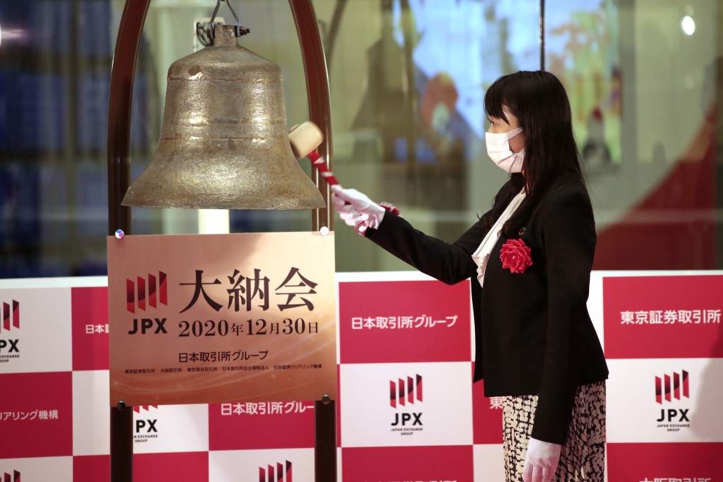 An employee rings the closing bell during a ceremony on Wednesday marking the last trading day of 2020 at the Tokyo Stock Exchange. Photo: JPX via AP