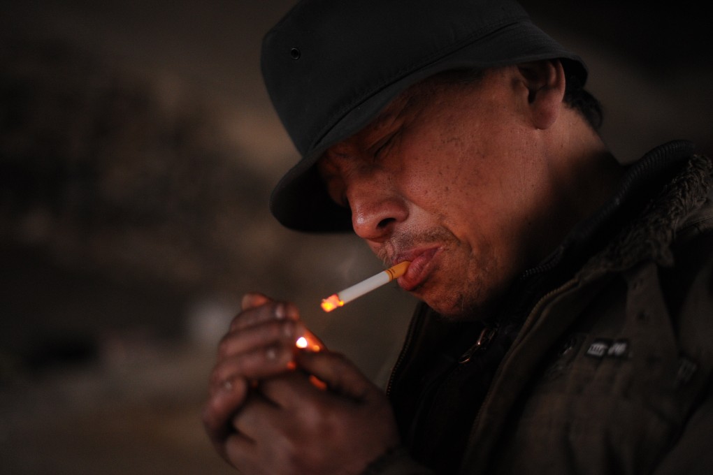 A homeless man lights up a cigarette in Hefei, Anhui province. In the study, those in poor areas had a 34.2 per cent smoking rate compared to the national average of 26.6 per cent. Photo: AFP