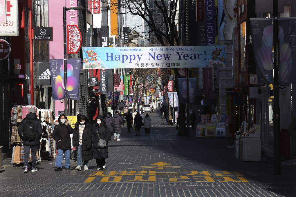 People wearing face masks walk along a shopping street in Seoul on Saturday. South Korea’s population shrank last year for the first time in its history. Photo: AP