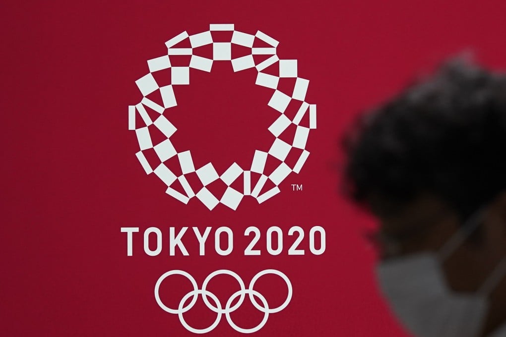 A pedestrian wearing a protective mask walks past a poster for the Tokyo 2020 Olympic Games. The event was delayed for one year until July, 2021. Photo: EPA