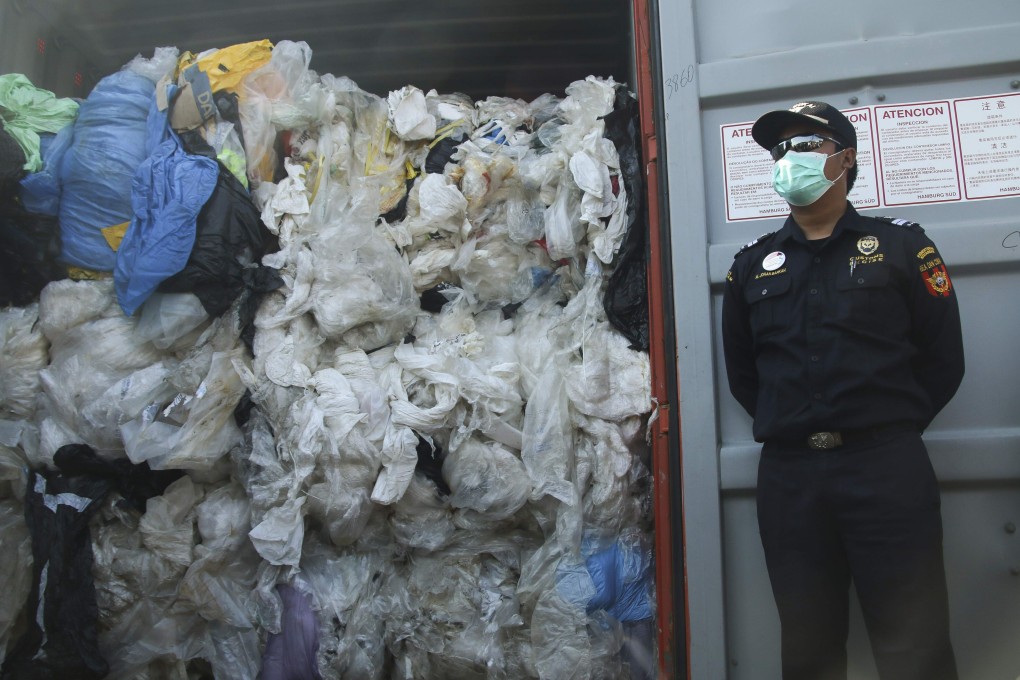 An officer stands next to a container full of illegal imported plastic waste in Batam, Indonesia, in July 2019, when the country returned seven shipping containers of such waste to France and Hong Kong. Southeast Asia has been a hotbed of illicit plastic waste trade since China enacted a ban on “foreign waste”. Photo: AFP
