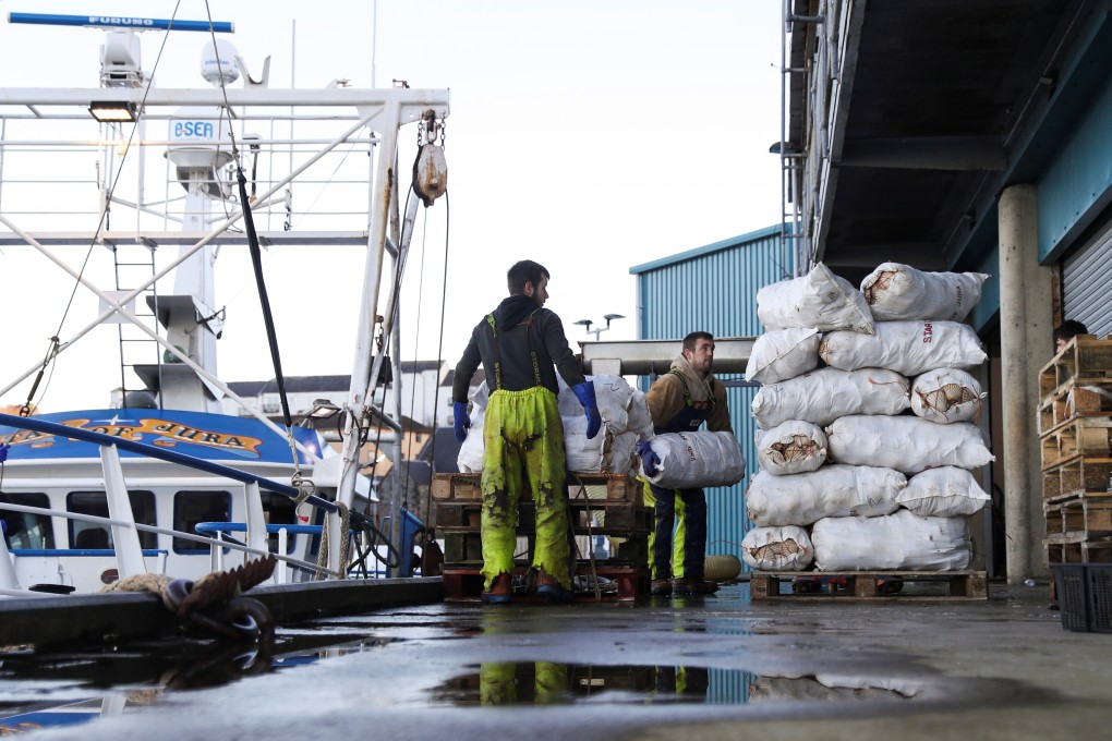 Workers unload sacs of scallops from a fishing boat at Oban in Scotland, after Britain left the EU. Photo: Reuters