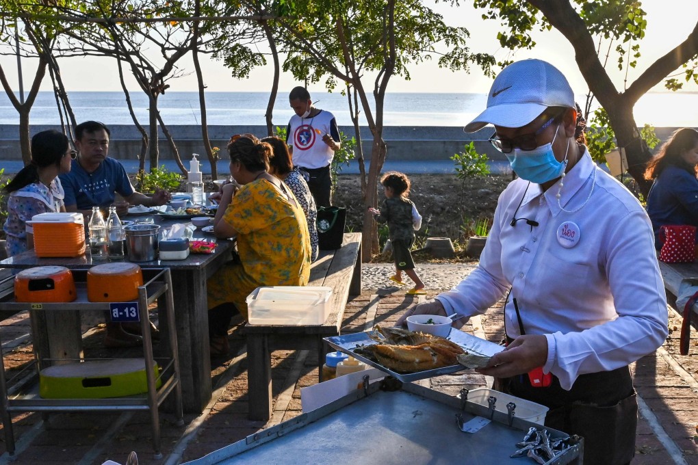 A waitress with a face mask serves customers at a restaurant in Bangpu, Thailand. Photo: AFP