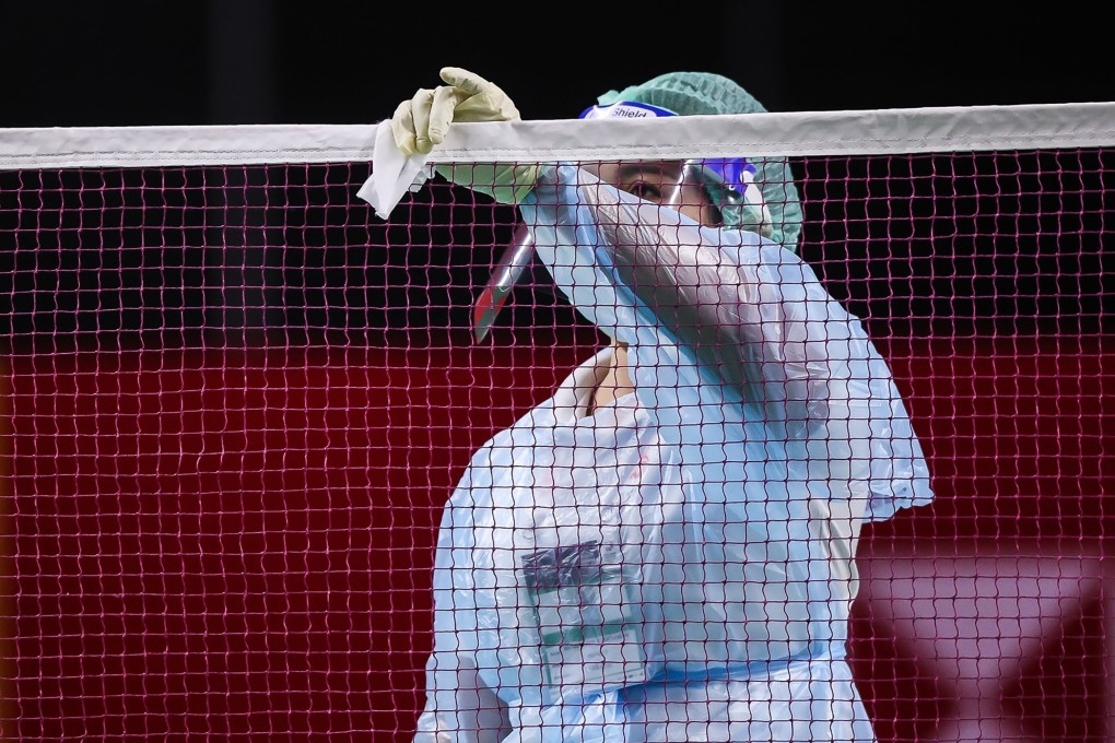 An official wearing a face mask and shield while cleaning the net as a preventive measure against the spread of the Covid-19 coronavirus, ahead of the Thailand Open in Bangkok. Photo: AFP