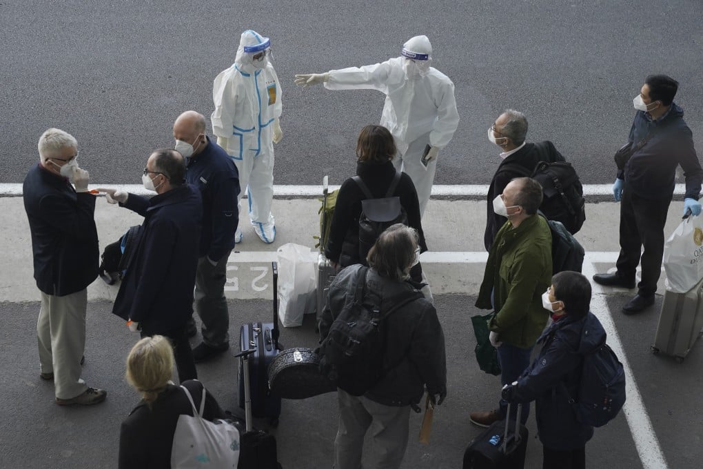 A worker in protective gear directs members of the World Health Organization team on their arrival at the airport in Wuhan on Thursday. Photo: AP