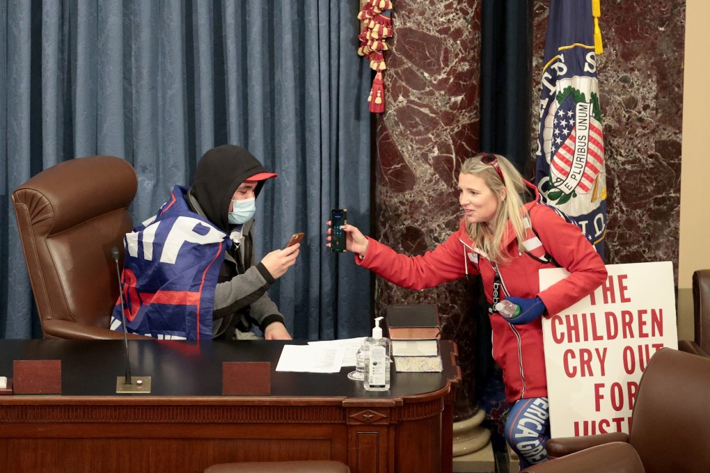 A protester sits in the Senate chamber in Washington after supporters of US President Donald Trump stormed the US Capitol building on January 6, stopping a joint session being held to ratify President-elect Joe Biden’s Electoral College win. Photo: Getty Images/TNS