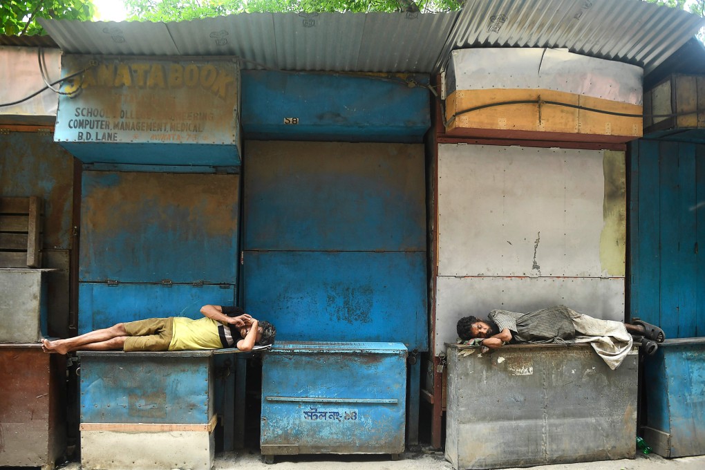 Men resting in front of closed book stalls during a coronavirus lockdown in Kolkata on August 31, 2020. Photo: AFP
