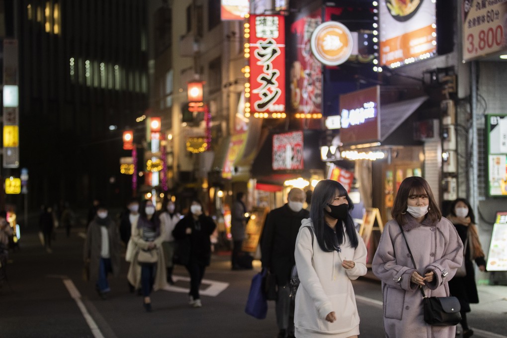 People wearing face masks walk on a street filled with restaurants and bars during a coronavirus state of emergency in Tokyo on Thursday. Photo: AP