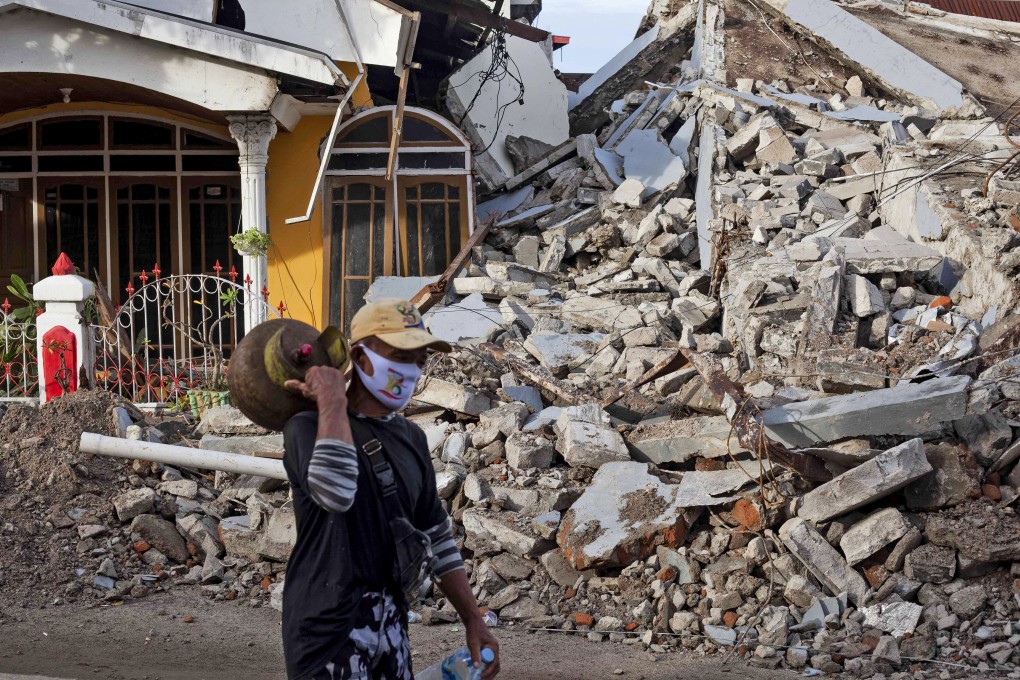 A man walks past a house that collapsed in Friday's earthquake in Mamuju, West Sulawesi. Photo: AP