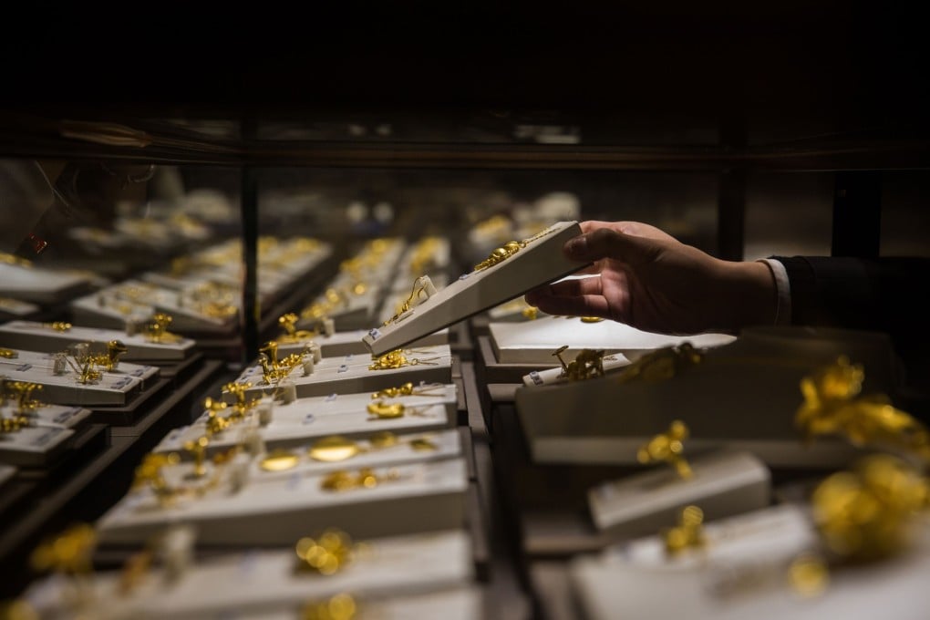 An employee handles a gold jewellery set inside a display case at a Chow Tai Fook shop in Hong Kong. The gold and jewellery retailer has more than 4,000 outlets worldwide. Photo: Bloomberg