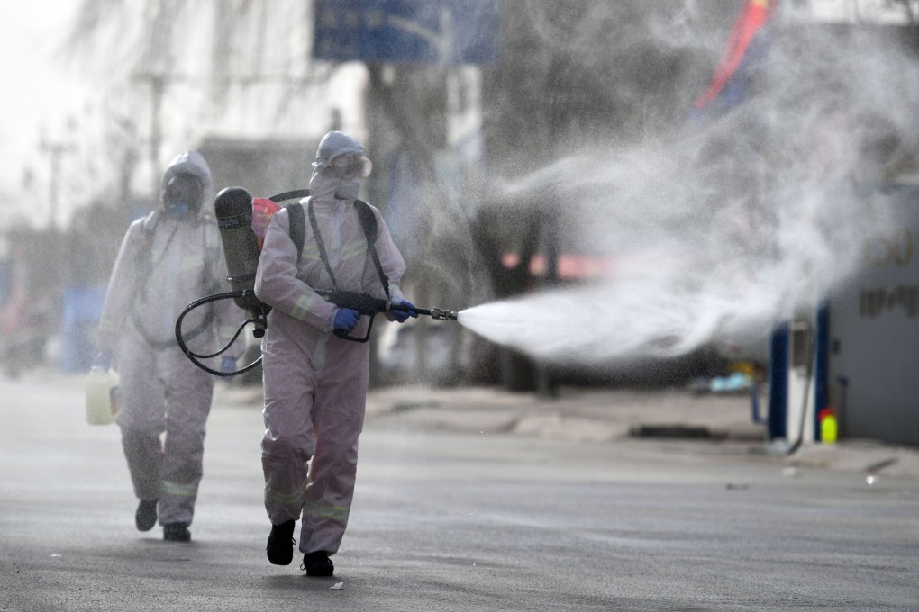 Workers spray disinfectant on a street in Shijiazhuang’s Gaocheng district. Photo: STR/CNS/AFP