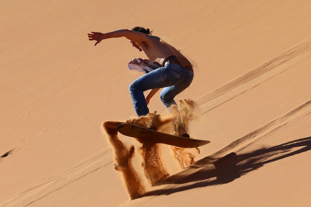 A tourist sandboarding in the Dubai desert, in the United Arab Emirates. Dubai has flung its doors open, branding itself as a sunny, quarantine-free escape from Covid-19 – despite a sharp rise in cases. Photo: AFP