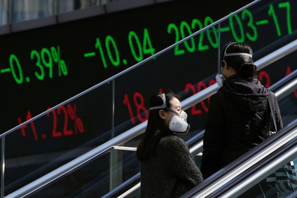 Pedestrians near an overpass with an electronic board showing stock information at the Lujiazui financial district in Shanghai on March 17, 2020. Photo: Reuters