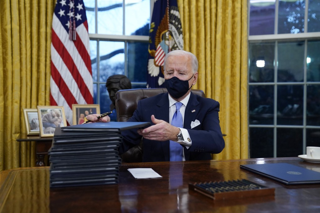 US President Joe Biden signs his first executive orders in the Oval Office of the White House on January 20. Photo: AP