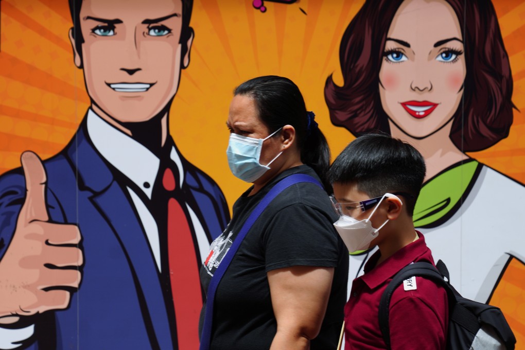 A domestic helper accompanies a young boy as they walk past a billboard in Wan Chai. Photo: Sam Tsang