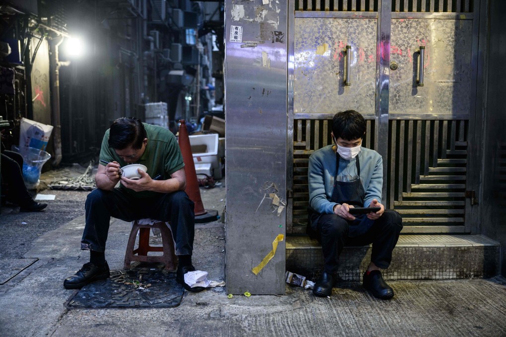 A man eats his dinner in an alleyway as another checks his phone in a residential doorway in Hong Kong on January 4. Hong Kong’s jobless rate hit a 16-year high in the final quarter of 2020. Photo: AFP