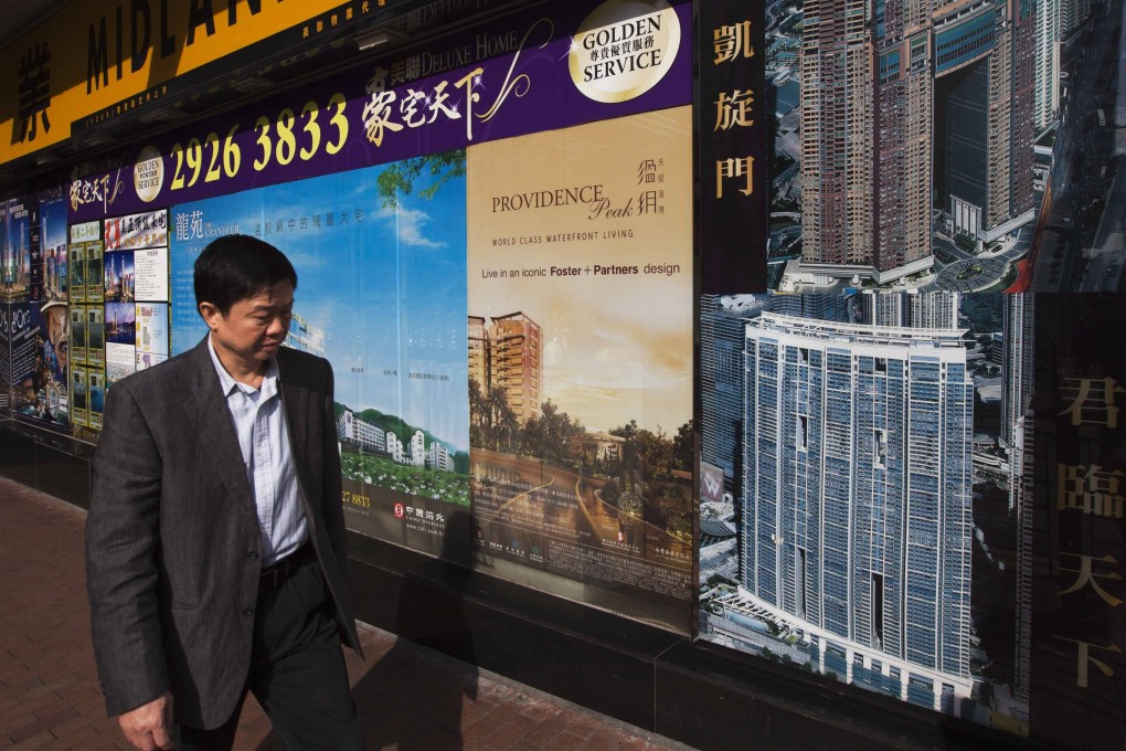 A man walks past a real estate agency displaying advertisements of residential developments near West Kowloon. Prospective buyers should exercise care when assessing promotional messages. Photo: Reuters