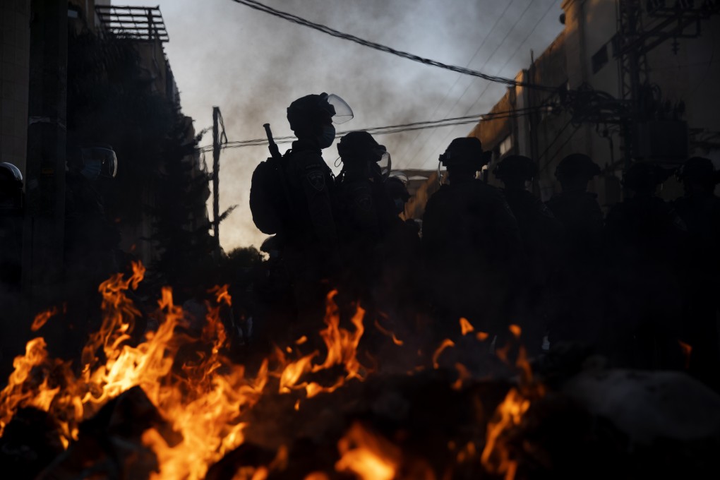 Israeli police officers stand guard next to burning rubbish during clashes with ultra-Orthodox Jews in Bnei Brak, Israel on Sunday. Photo: AP