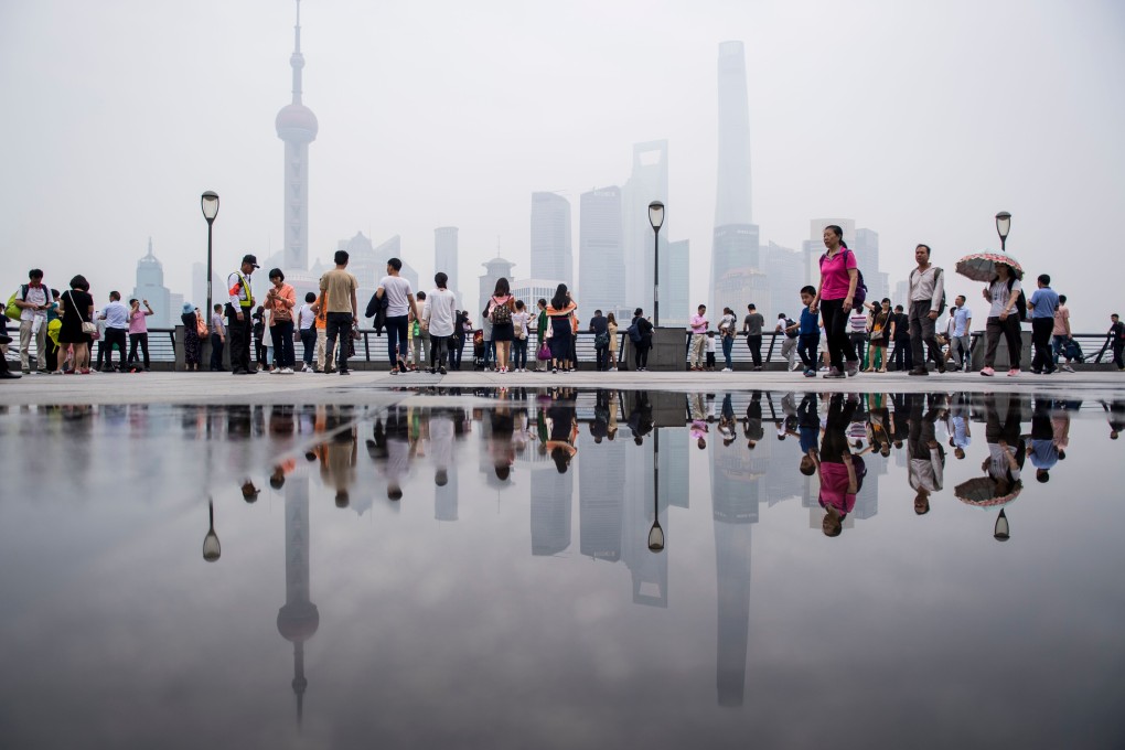 Tourists enjoy the view at the promenade on the Bund along the Huangpu River, seen against the skyline of the Lujiazui financial district in Shanghai, on May 29, 2018. Photo: AFP