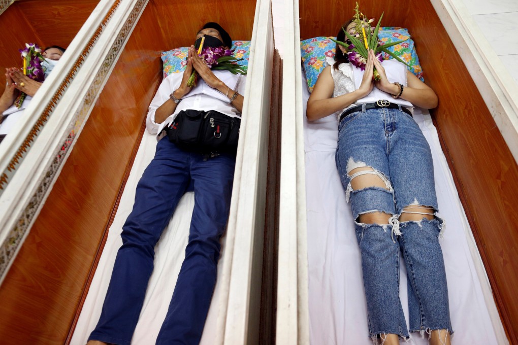 Devotees lie down and pray inside coffins to ‘trick death and improve their luck’ at a temple in Bangkok. Photo: Reuters