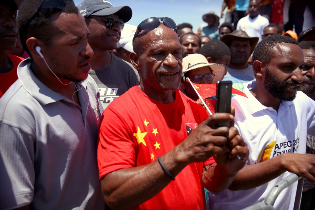 A Papua New Guinean man wearing a shirt with the Chinese and Papua New Guinea flags takes a photo on his mobile phone during the 2018 opening of Independence Boulevard in Port Moresby. Photo: Reuters