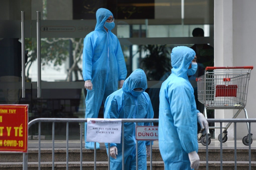 Medical workers in protective suits stand outside a quarantined building amid the coronavirus outbreak in Hanoi. Photo: Reuters