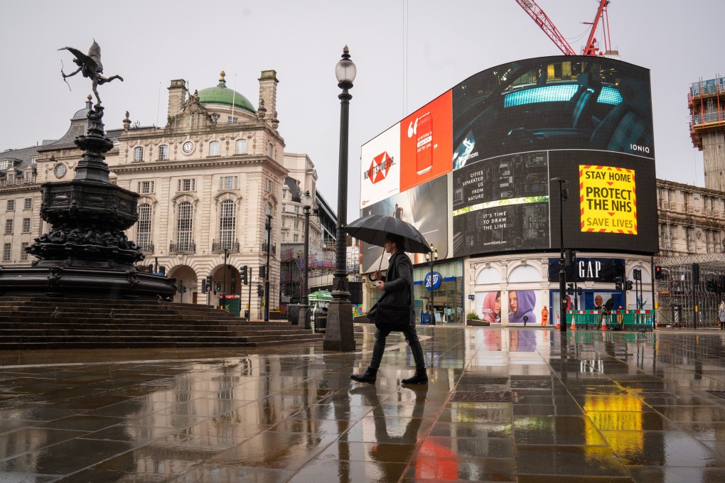 A man with an umbrella walks through Piccadilly Circus in London. Photo: DPA